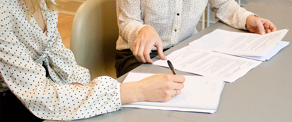 Two people signing documents. family justice counsellor JSL Blog